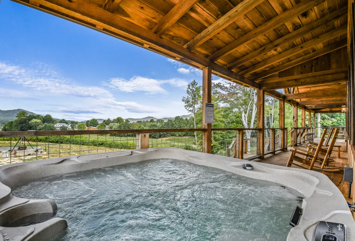 A tranquil wooden deck featuring a hot tub, swing set, and expansive mountain views. The hot tub sits ready for a restorative soak after a day of exploration, while the deck offers space to relax and savor the landscape.