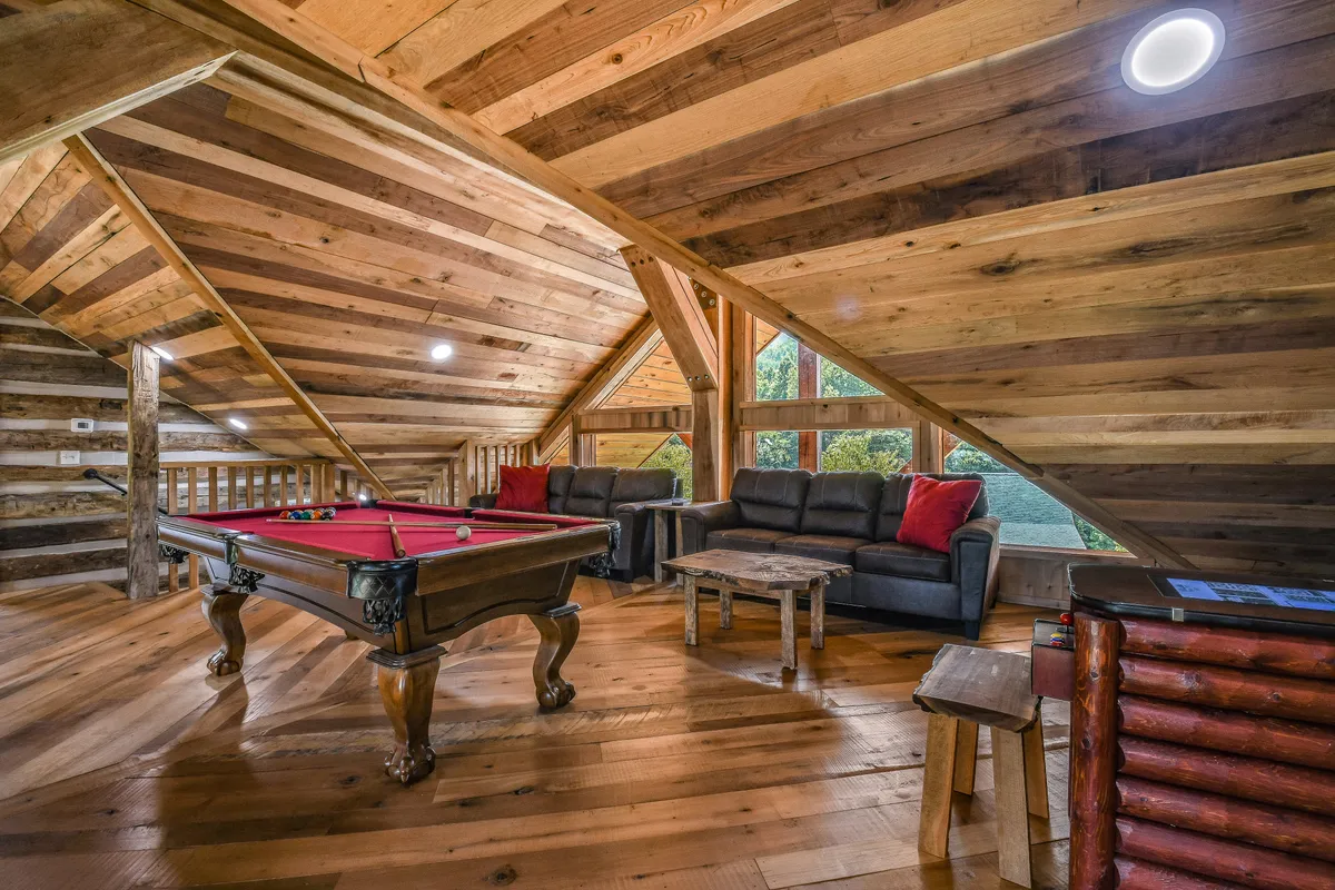 This image features a vibrant game room with a pool table, cozy sofas, and large windows letting in natural light. The setup is designed for both relaxation and social gatherings, emphasizing friendly competition and leisure.