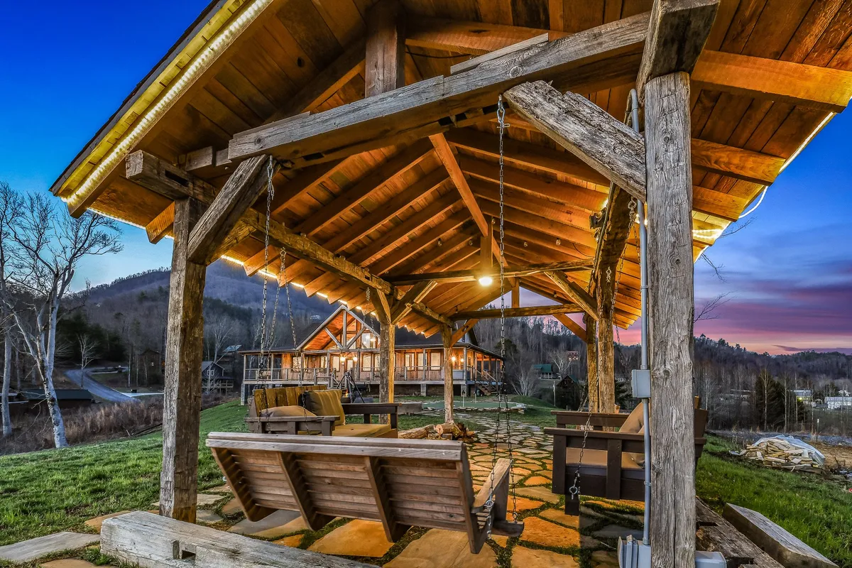 An open pavilion structure with comfortable wooden swing chairs, a stone pathway, and sweeping mountain views in the background. The area invites relaxation, conversation, and stargazing, making it ideal for group activities and quiet moments alike.